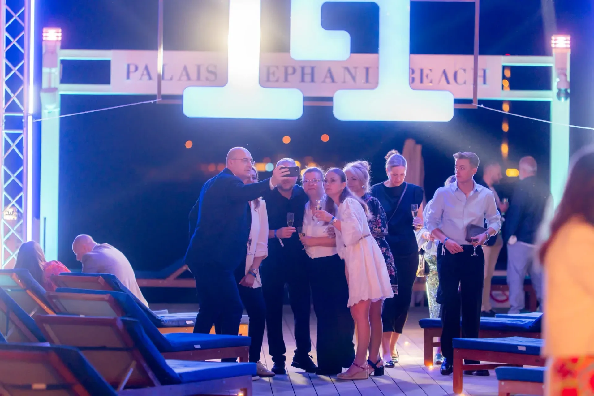 Gebr. Heinemann guests taking a selfie under the Palais Stéphanie Beach sign in Cannes, spontaneous group photo at a corporate gala evening.