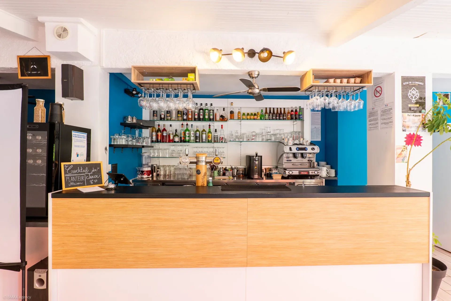 Intérieur du bar du camping La Ribière avec comptoir et étagères de bouteilles