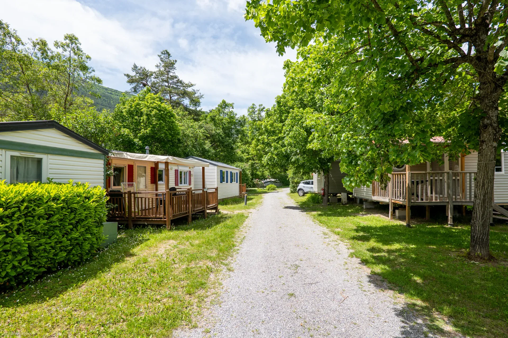 Allée du camping La Ribière avec mobil-homes et vue sur les montagnes