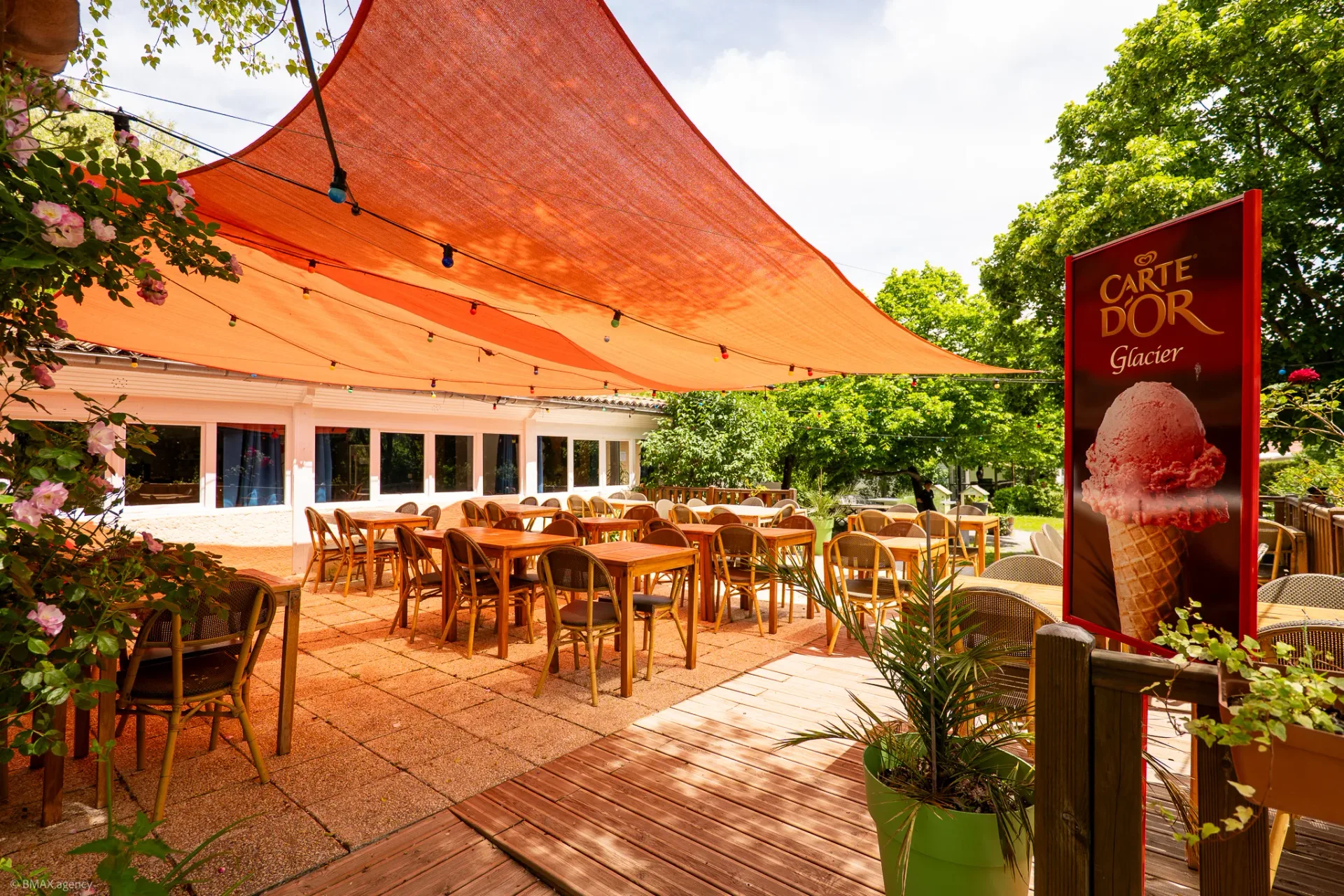 Terrasse du restaurant du camping La Ribière ombragée par une voile rouge