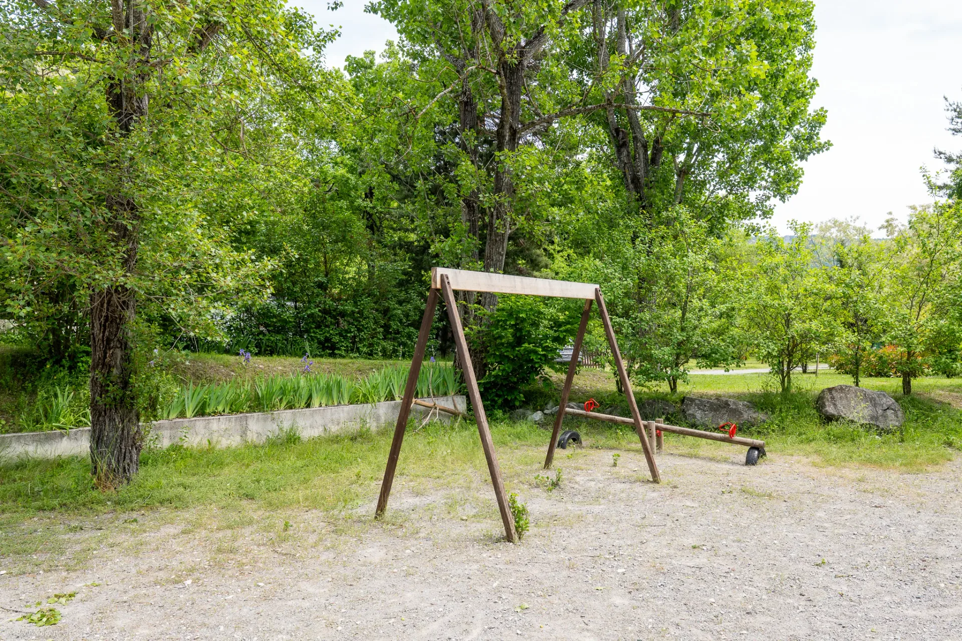 Balançoire en bois sur l'aire de jeux du camping La Ribière